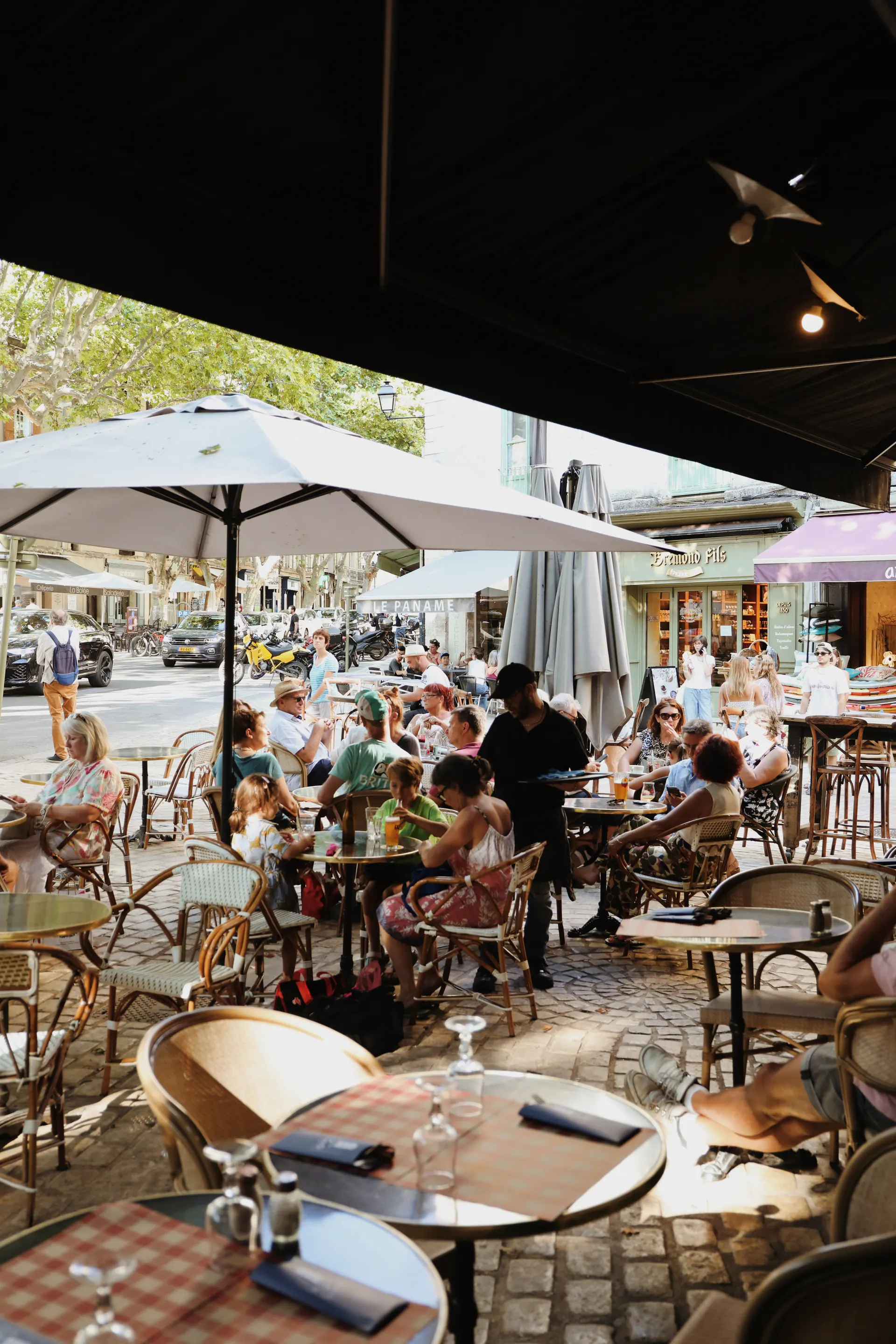 La terrasse du Vieux Café bondée sous les parasols, un jour de marché à Uzès